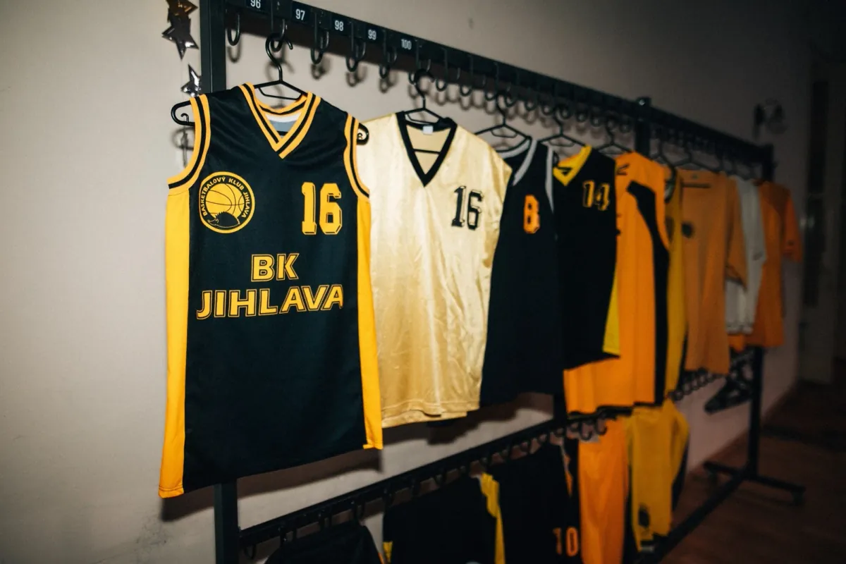 Historické klubové dresy na věšáku, v popředí černožlutý dres BK Jihlava s číslem 16.